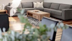 Una sala de estar moderna con un sofá seccional gris, una mesa de centro de madera y una mesita auxiliar.