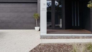 Un edificio moderno con fachada oscura, entrada de vidrio y una pequeña planta en maceta.