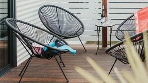 Un patio con dos sillas de alambre negro, una mesita y una botella.