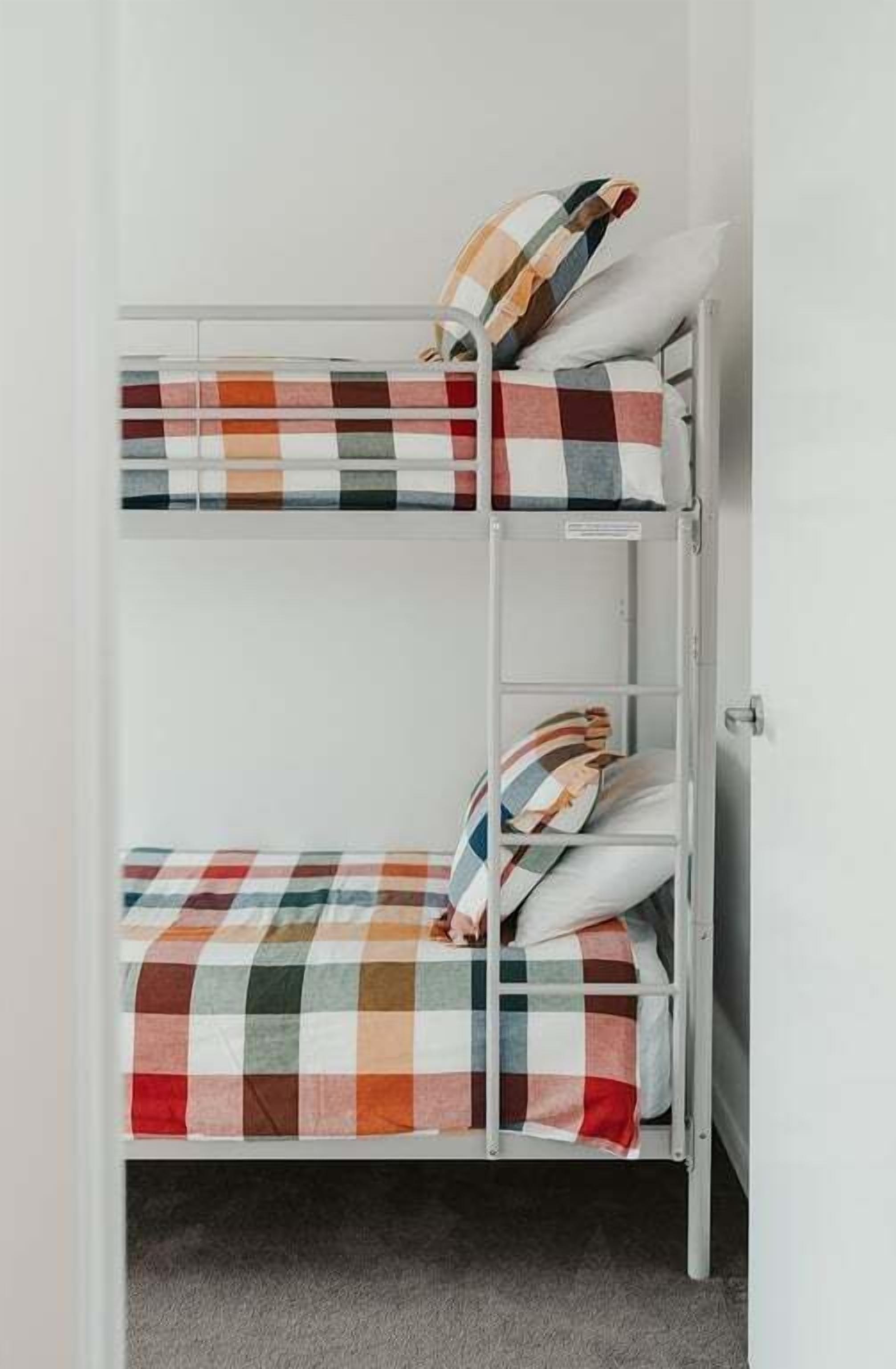 Una cama litera con ropa de cama y almohadas a cuadros.
