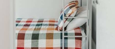 Una cama litera con ropa de cama y almohadas a cuadros.