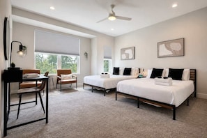 Une chambre d’hôtel avec deux lits, un bureau, une chaise et un ventilateur de plafond.