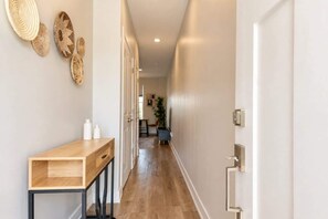 Un couloir avec une console en bois, une porte dotée d’une poignée et un mur orné de paniers tressés.