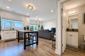 A modern kitchen with a central island, a dining area with a sofa, and a living room with a TV. - 4BR Warrenville Home w/ Patio & Garage | Sleeps 10 (Warrenville)