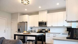 Uma cozinha moderna com armários brancos, eletrodomésticos de aço inoxidável e uma ilha central.