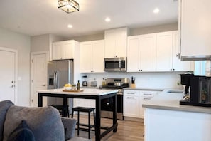 A modern kitchen with white cabinets, stainless steel appliances, and a central island. - 4BR Warrenville Home w/ Patio & Garage, Sleeps 10 (Warrenville)