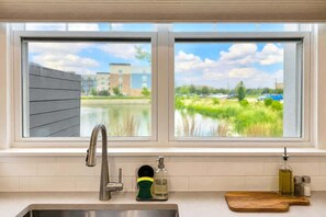 A kitchen with a window view of a water body and buildings. - 4BR Warrenville Home w/ Patio & Garage | Sleeps 10 (Warrenville)