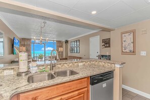 A kitchen with granite countertops, a dishwasher, and a view of the ocean. - Sand Dunes 1043 & 1044 (Myrtle Beach)