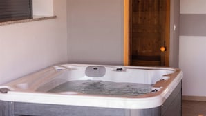Una bañera de hidromasaje en una habitación con una puerta de madera y un ventanal pequeño.