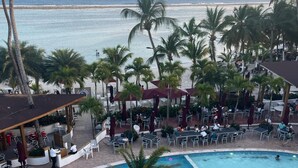 Ein Poolbereich mit Palmen, einer Bar und Blick auf den Ozean.