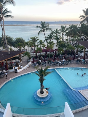 Een zwembad met palmbomen, een bar en uitzicht op de oceaan.