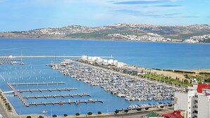 A marina with numerous boats docked, a pier, and a backdrop of hills and buildings. - The Overlook Tangier - Panoramic Sea and Kasbah View Downtown (Tanger)