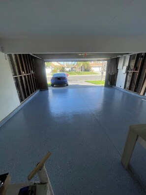 A garage with a blue car parked inside, a concrete floor, and a view of a residential street. - Beautiful Home in Moreno Valley (Moreno Valley)
