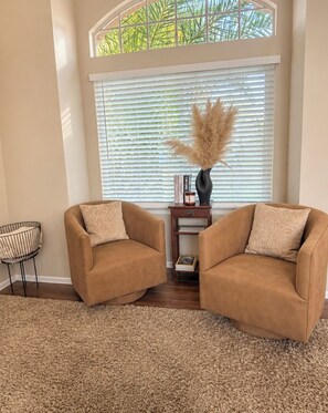 A room with two armchairs, a small side table with books, a vase with pampas grass, and a window with blinds. - Beautiful Home in Moreno Valley (Moreno Valley)