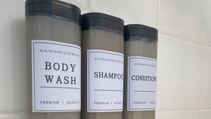 Tres botellas de gel de baño, champú y acondicionador sujetas a la pared.