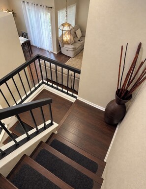 A staircase with a black railing, wooden steps, and a vase with sticks on the landing. - Beautiful Home in Moreno Valley (Moreno Valley)