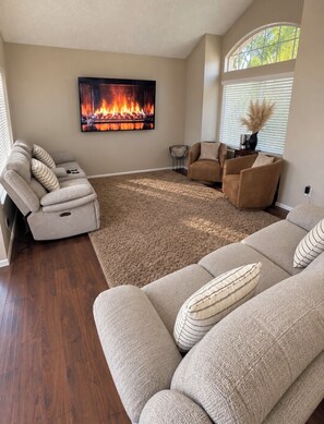 A living room with a fireplace, a large sofa, a chair, and a rug.