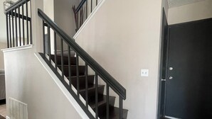 A staircase with a black railing, a door, and a vent on the wall. - Beautiful Home in Moreno Valley (Moreno Valley)