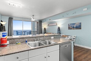 Eine moderne Küche mit Granit-Arbeitsplatten, Edelstahl-Spülen und Blick auf den Ozean.