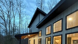 A modern house with a wooden deck, large windows, and a view of the surrounding trees. - RRG Cabin - 2 King Suites + Ride-In Access (Stanton)