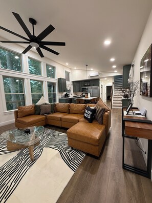 A modern living room with a sectional sofa, a glass coffee table, and a zebra-patterned rug.