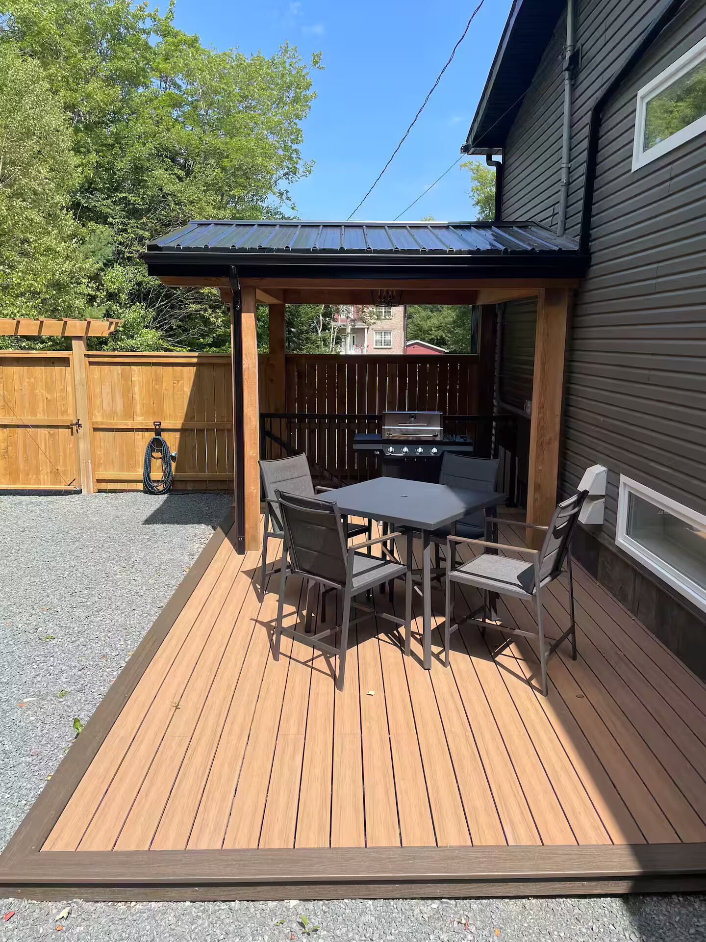 A wooden deck with a covered patio area, a barbecue grill, and outdoor seating.
