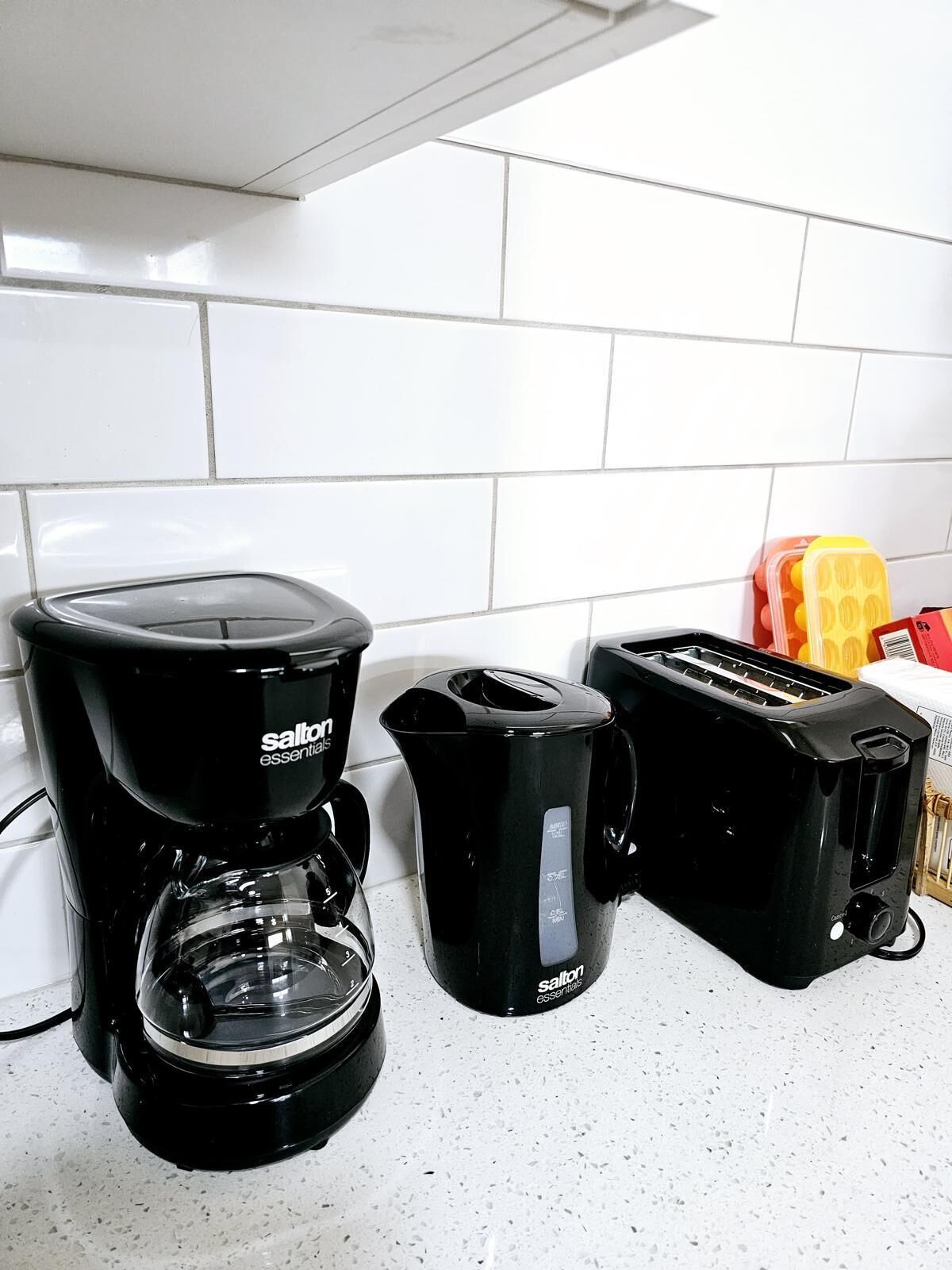 A kitchen with a coffee maker, a kettle, and a toaster on the counter.