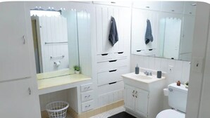 Un baño con inodoro, lavamanos, espejo y armarios de almacenamiento.