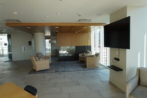 Un hall d’entrée spacieux doté d’un téléviseur à écran plat, de sièges confortables, d’un plafond en bois et d’une grande fenêtre.