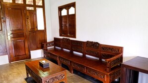 Ein Zimmer mit einer Holzsofa, einem passenden Holztisch und einer Kommode mit aufwendigen Schnitzereien.