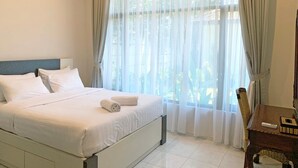 Ein Hotelzimmer mit Bett, Stuhl, Tisch und einem Vorhangfenster.