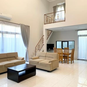 A spacious living area with a sofa set, a coffee table, and a dining table with chairs. - The Nalaya Hotel & Resto (Borobudur)