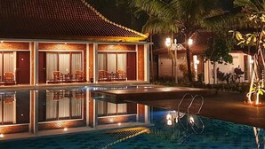 Ein Hotel mit Schwimmbad, Palmen und einem Ziegeldach.