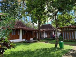 A traditional house with a tiled roof, surrounded by lush greenery and a well-maintained lawn. - The Nalaya Hotel & Resto (Borobudur)