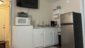 A compact kitchen with a microwave, coffee maker, and refrigerator.