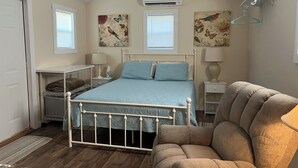 A bedroom with a bed, a chair, a desk, and a radiator.