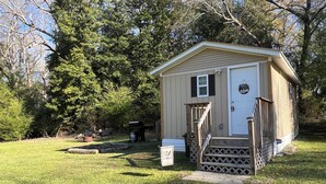 A small, single-story shed with a door, a small porch with steps, and a mailbox.