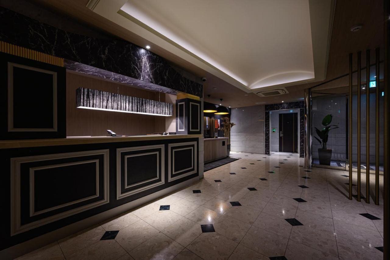 A hotel lobby with a reception desk, marble flooring, and a modern interior design.