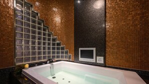 Une salle de bain moderne avec une baignoire entourée de parois en verre, un panneau de commande et un mur recouvert de carreaux.