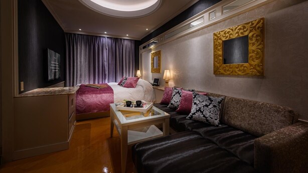 Une chambre d’hôtel comprenant un lit, un canapé, une petite table, un miroir et une œuvre d’art accrochée au mur.