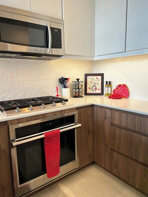 Una cocina con electrodomésticos de acero inoxidable, armarios de madera, un microondas y un cuadro en la encimera.