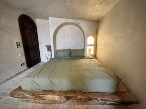 A room with a bed, a wooden door, and a wall-mounted light fixture. - Private Oasis Roof (Giza)