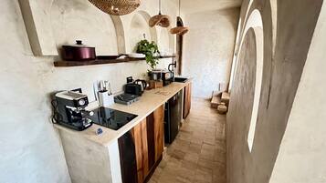 Una cucina con piano cottura integrato, una moka e lampade di vimini appese.