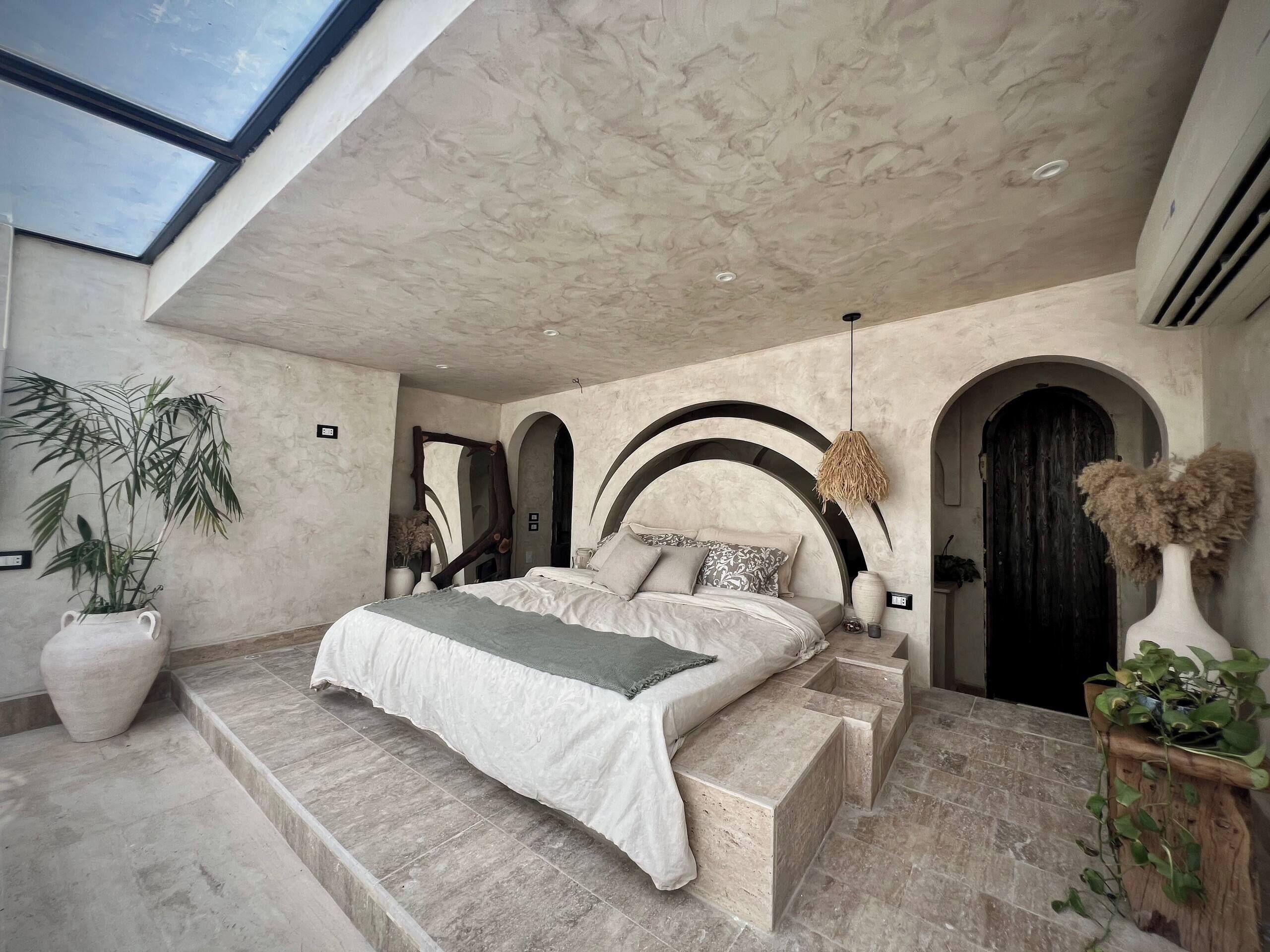 Un dormitorio moderno con tragaluces, una cama grande y una escalera que lleva a un nivel superior.