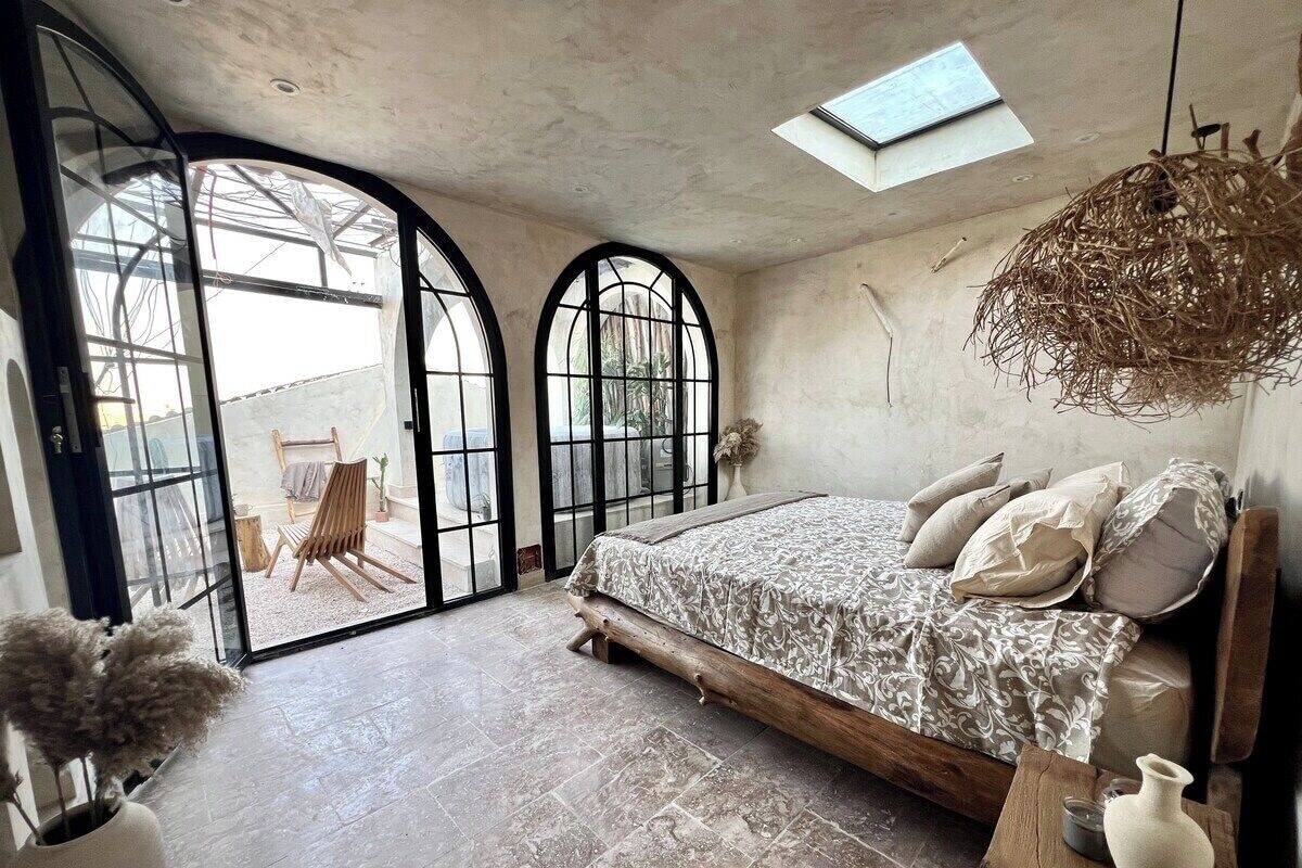 A bedroom with a bed, a skylight, a large window, and a view of the outside.