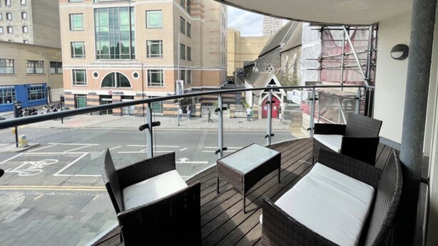 A balcony with wicker furniture, a view of a city street, and a building with a red door. - 2-Bed 2-Bath Sea-View Balcony Apt inc Sun Terrace minutes to Sea, Station, Shops (Brighton and Hove)