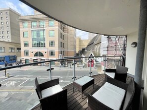 A balcony with wicker furniture, a view of a city street, and a building with a red door. - 2-Bed 2-Bath Sea-View Balcony Apt inc Sun Terrace minutes to Sea, Station, Shops (Brighton and Hove)