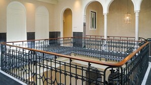 A spacious interior with a high ceiling, ornate iron railings, and a central open area. - Mercer Plaza Sevilla (Seville)