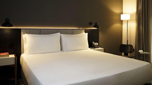 A hotel room with a large bed, two bedside tables, a nightstand, a lamp, and a telephone. - Mercer Plaza Sevilla (Seville)