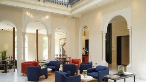 A spacious lobby with high ceilings, large windows, and a central seating area with sofas and tables. - Mercer Plaza Sevilla (Seville)